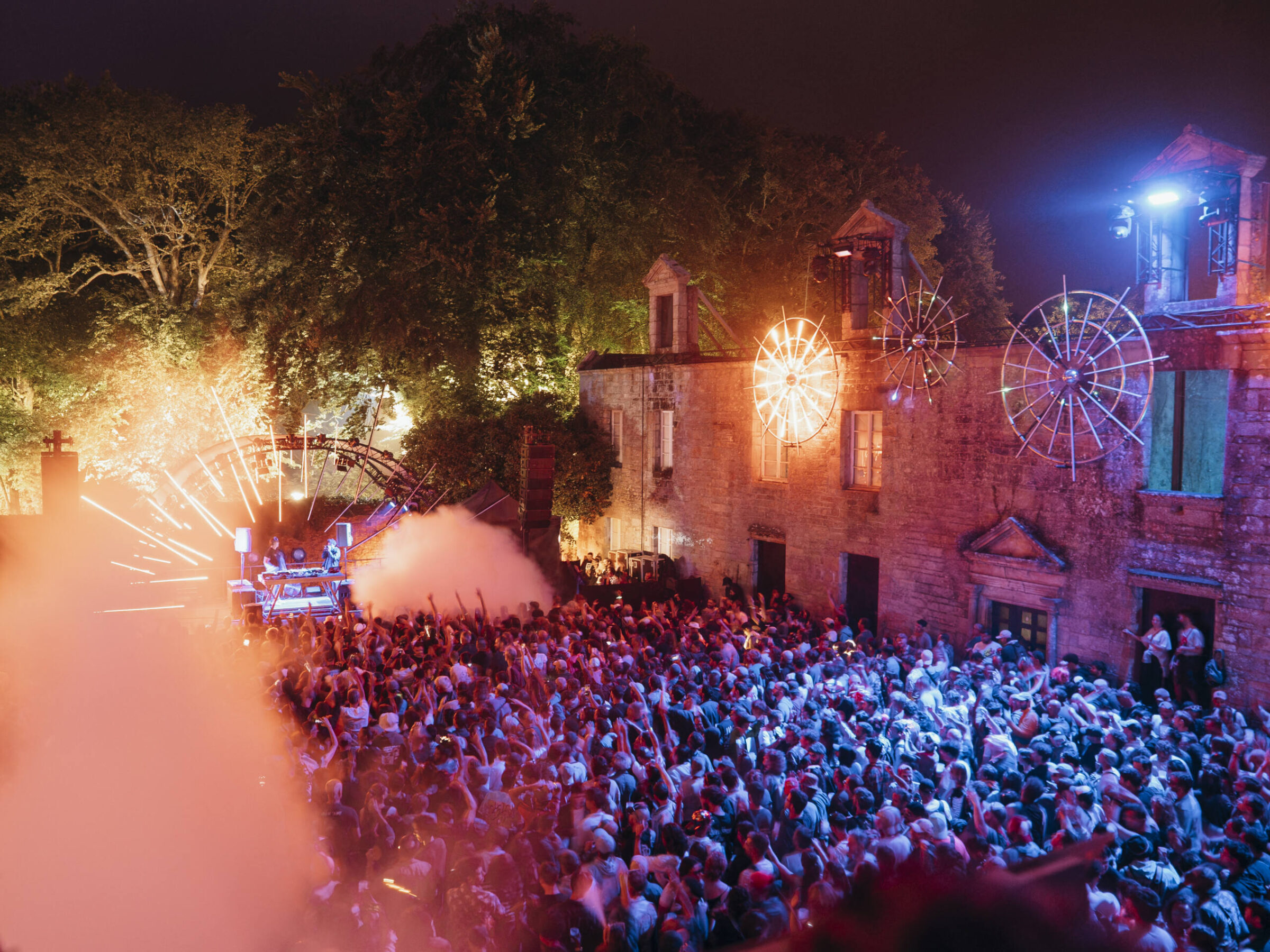Foule du festival Astropolis la nuit, devant le manoir illuminé