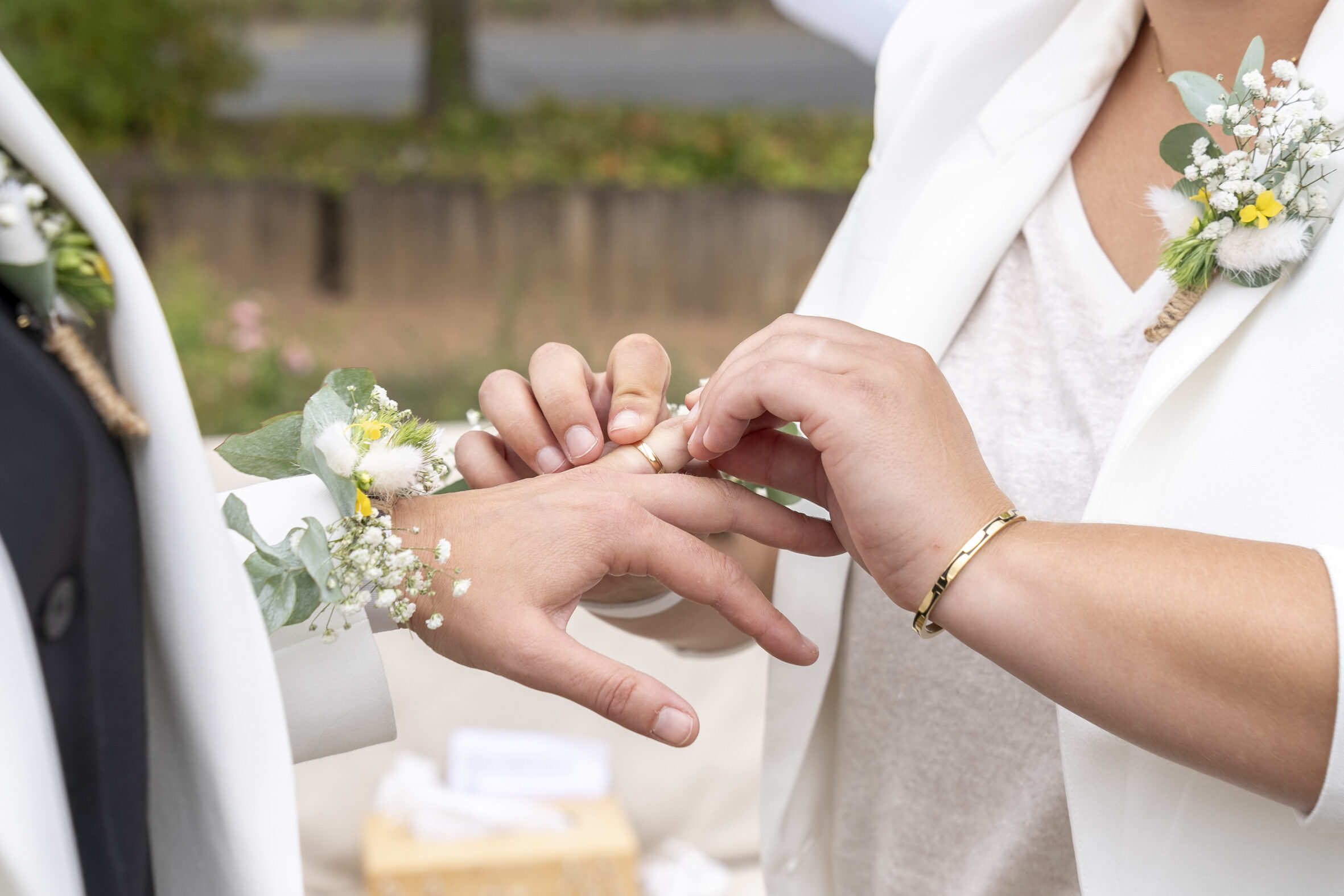Échange des alliances entre deux mariées, boutonnières de fleurs blanches