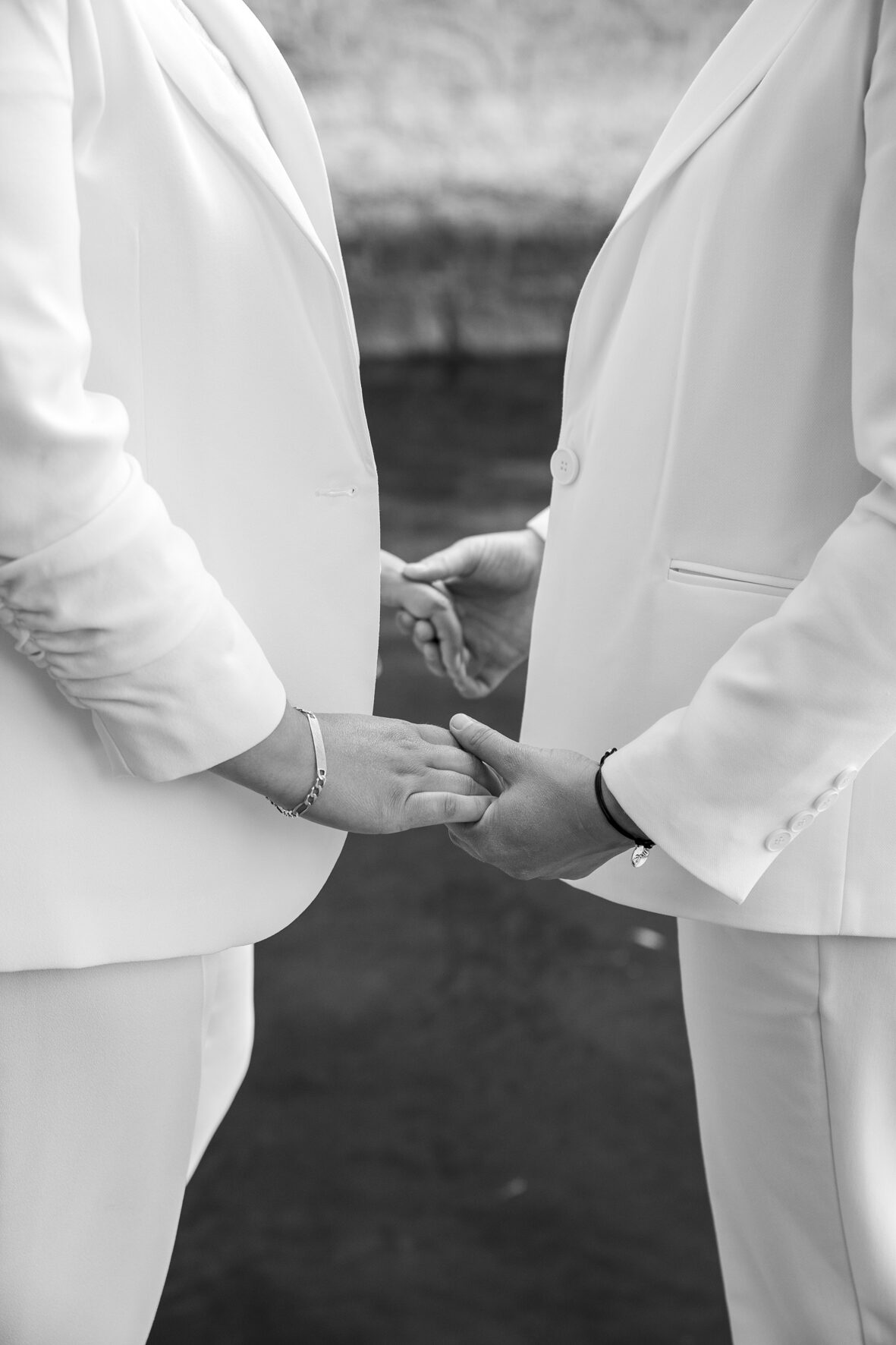 Deux mariées en tailleur blanc se tenant les mains, noir et blanc