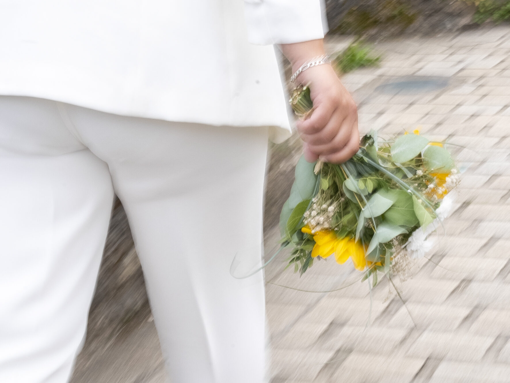 Mariée en tailleur blanc tenant son bouquet de tournesols
