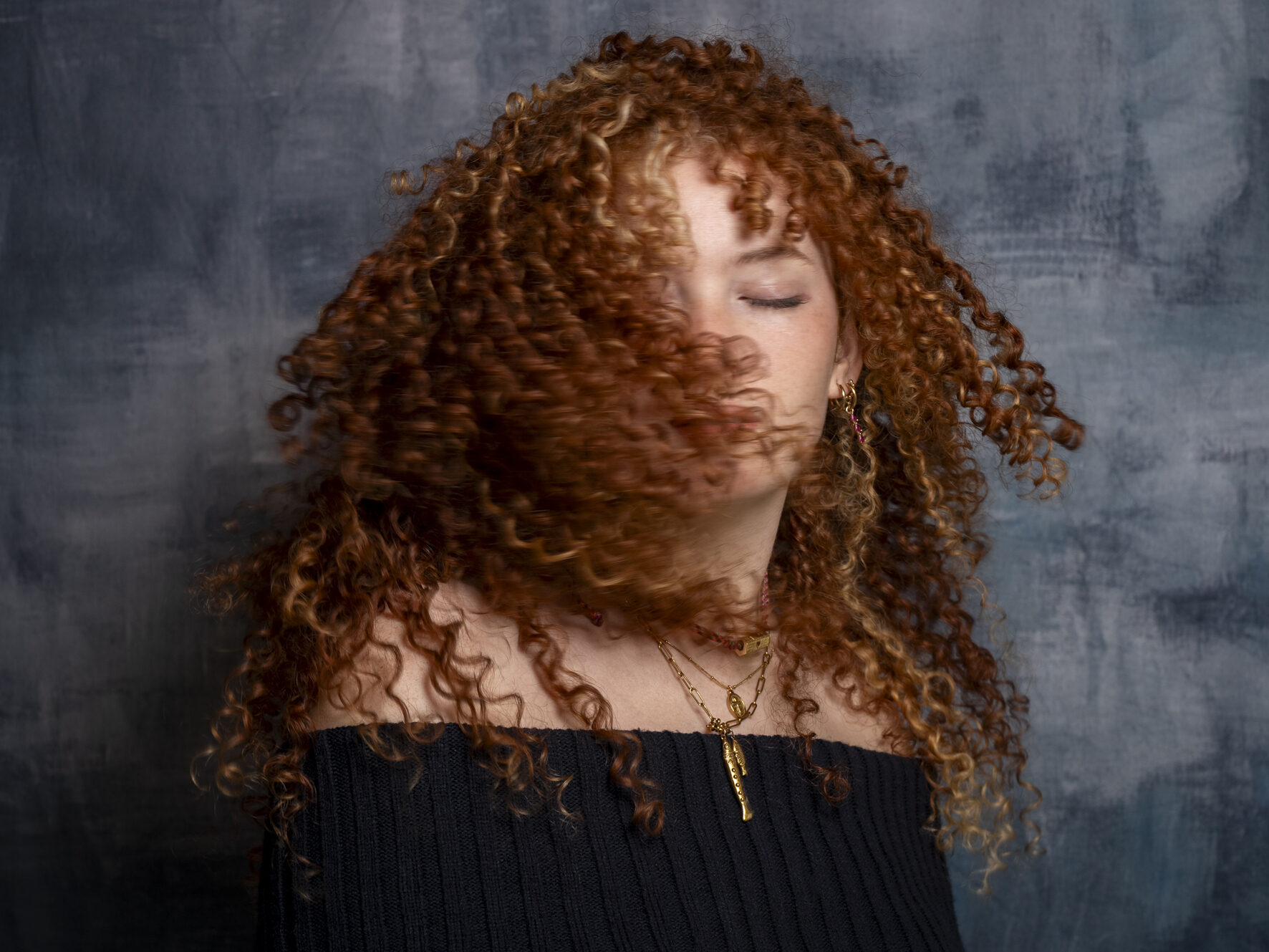 Jeune femme aux cheveux roux bouclés en mouvement, portrait studio