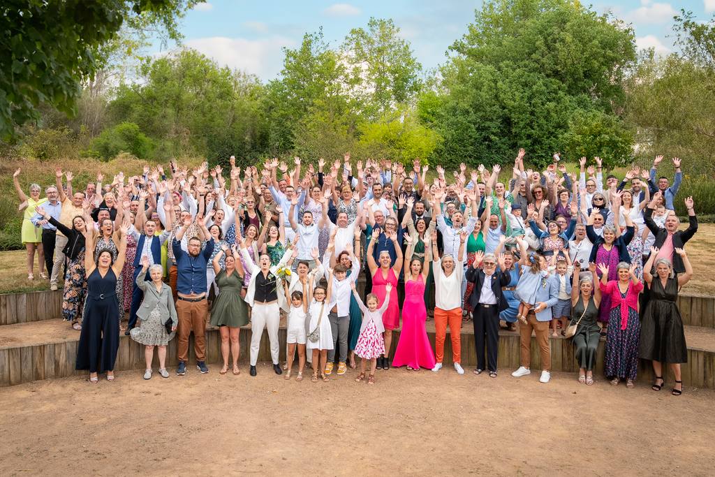 Grande photo de groupe au Fuilet : tous les invités lèvent les bras autour des mariées