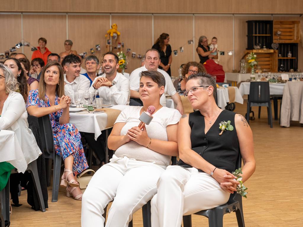 Les mariées assises face aux invités pendant les discours de la soirée