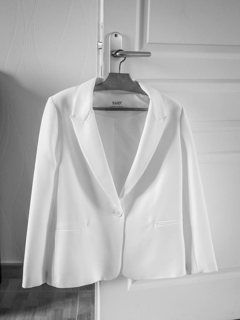 Veste de tailleur blanche accrochée à une porte, préparatifs de mariage, noir et blanc