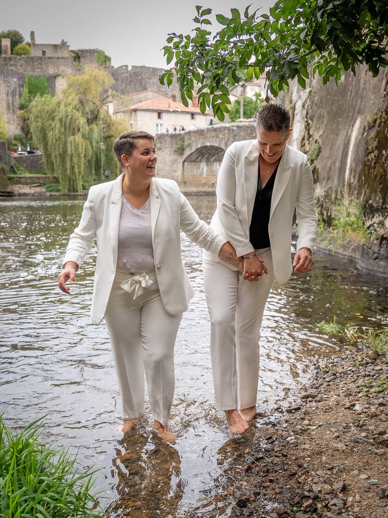 Les mariées marchent pieds nus dans la Sèvre à Clisson, main dans la main
