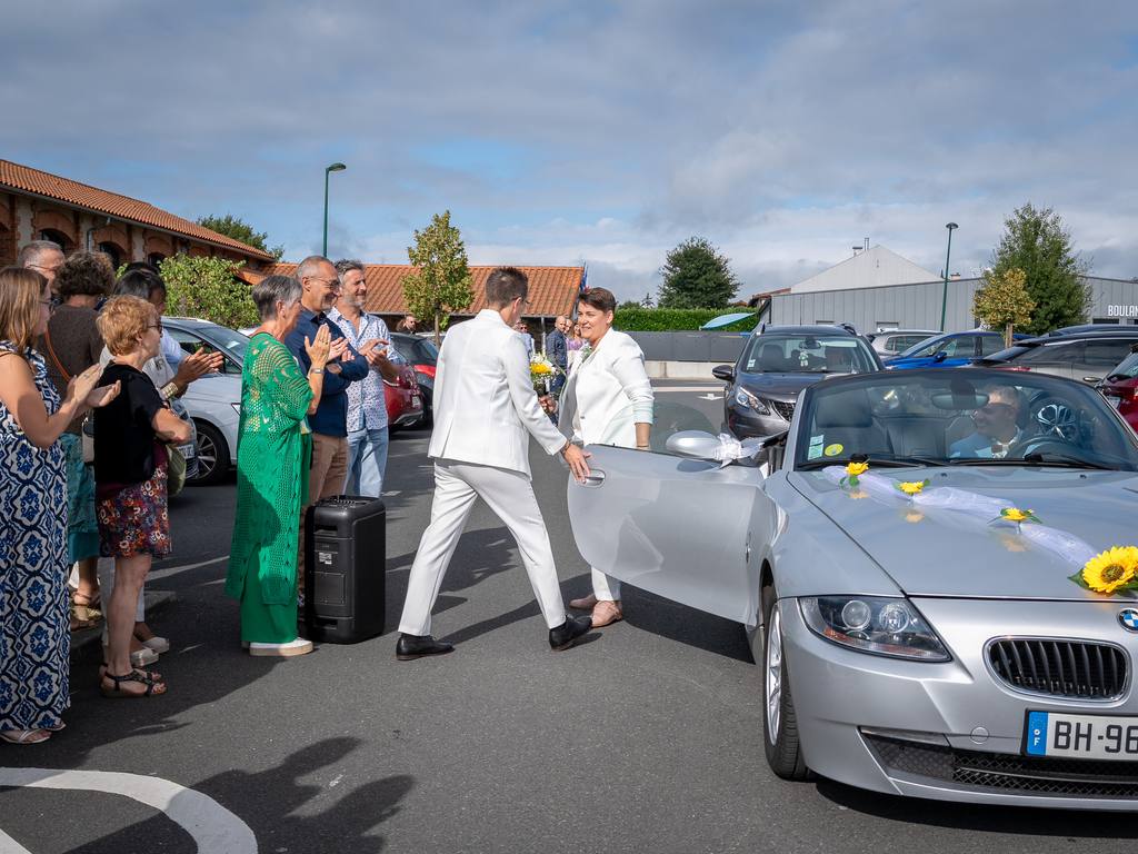 Arrivée de la mariée en cabriolet décoré de tournesols, accueillie par les invités