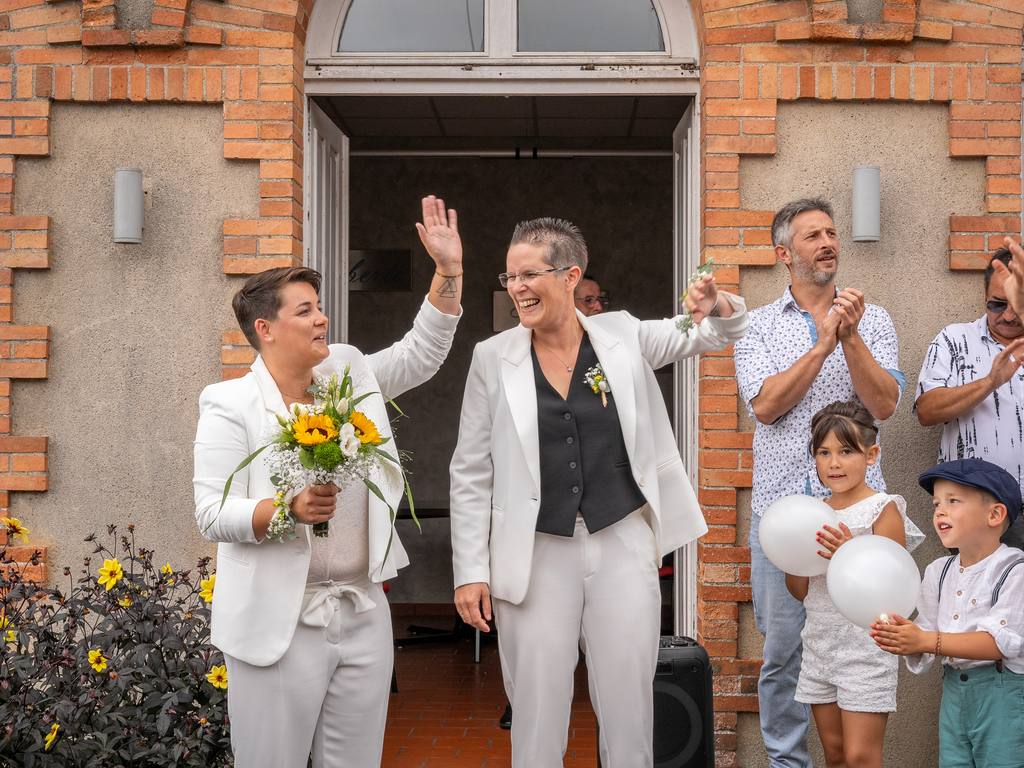 Sortie de la mairie du Fuilet : les deux mariées saluent leurs proches, bouquet de tournesols à la main