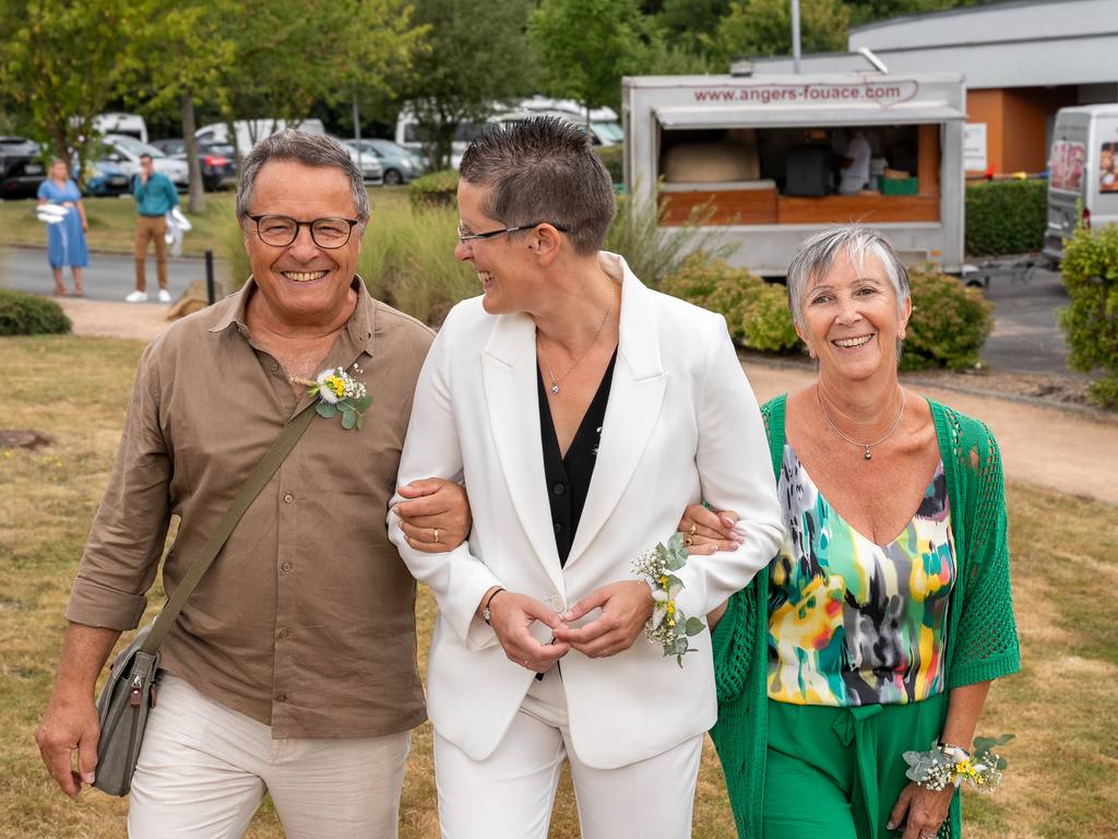 Une mariée arrive à la cérémonie au bras de ses parents