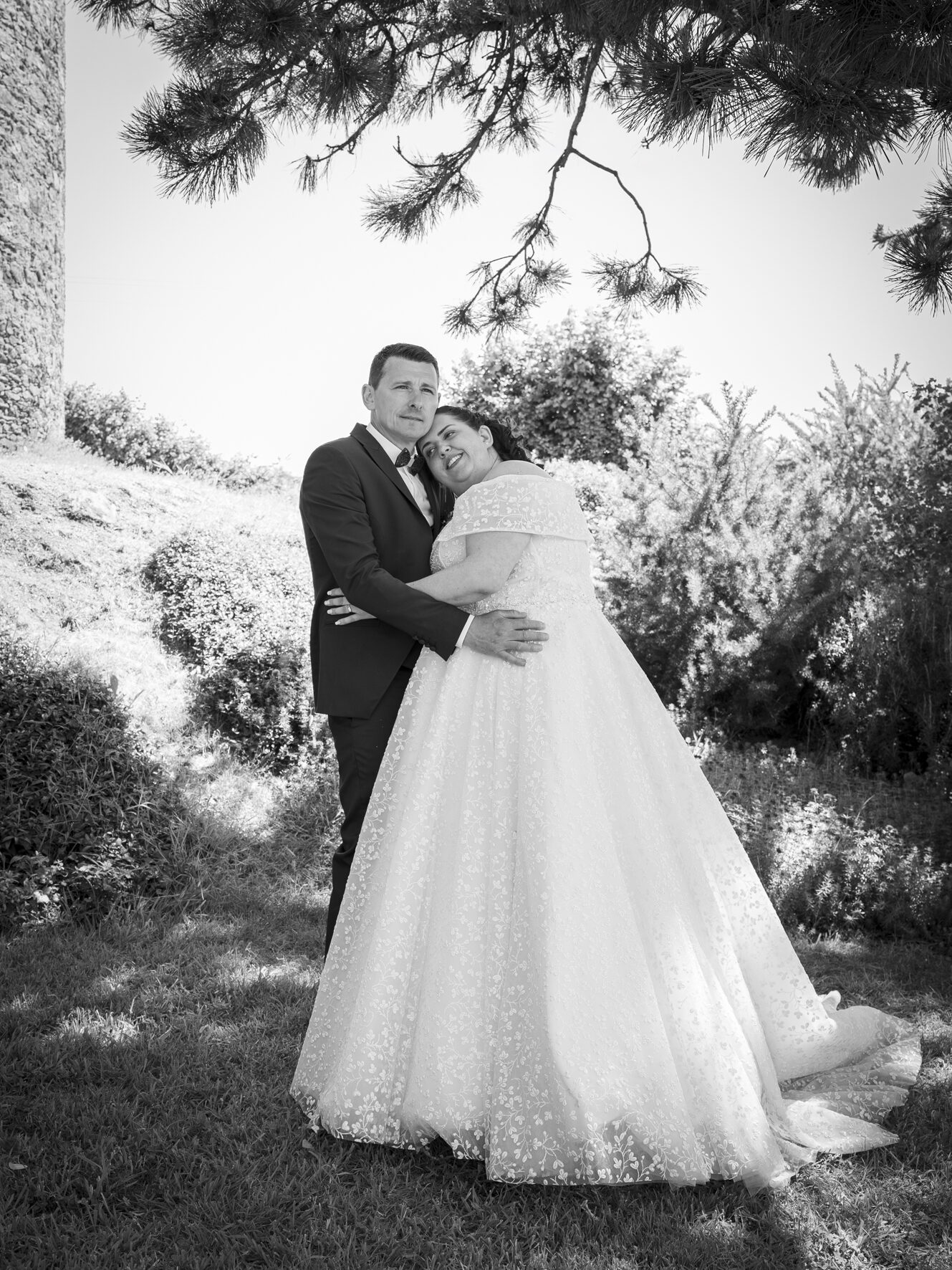 Mariés enlacés sous un pin, robe de mariée pailletée, noir et blanc