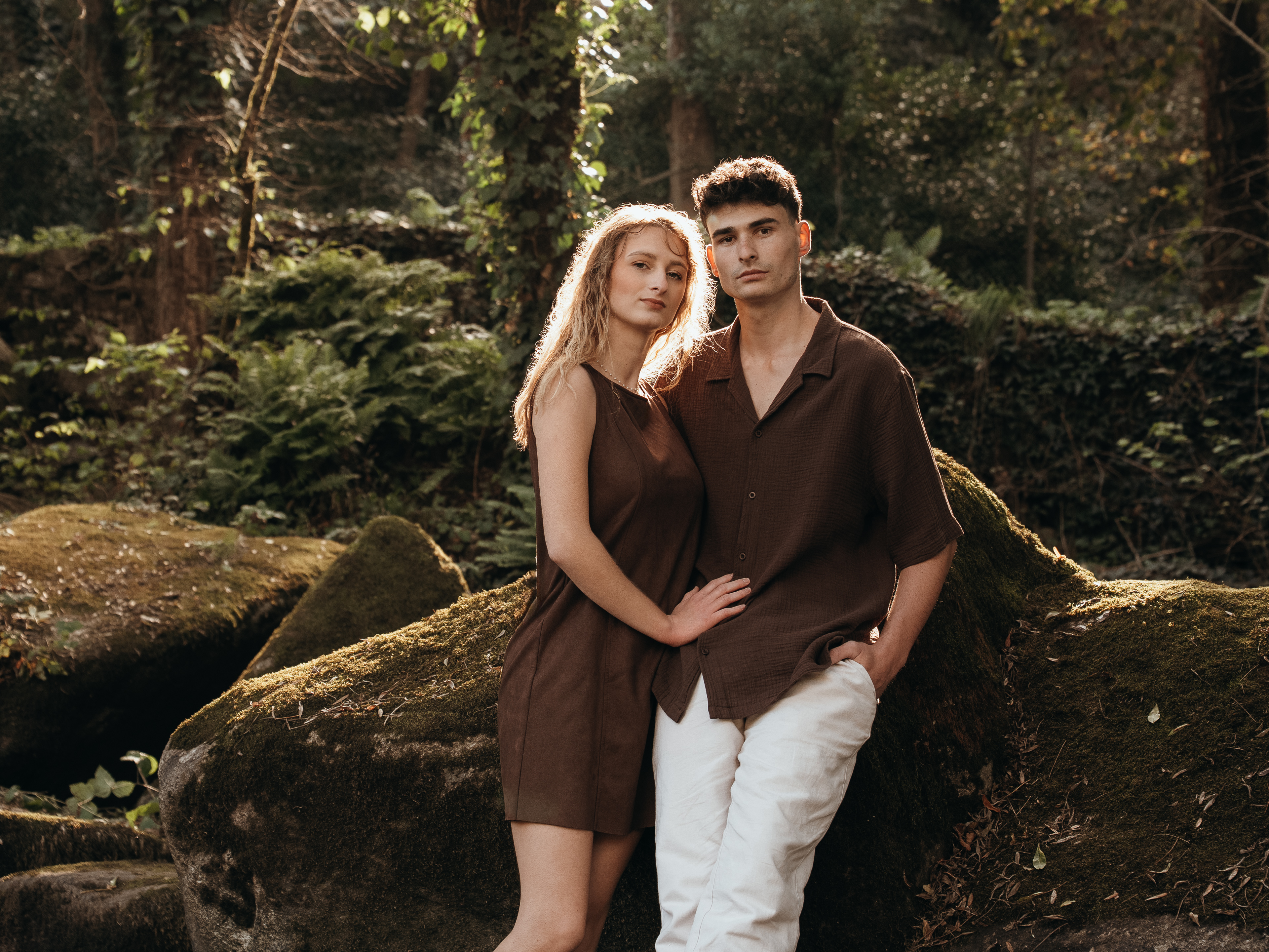 Couple enlacé contre un rocher moussu en forêt